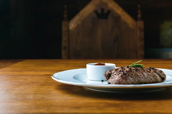 Délicieux steak grillé au romarin et sauce barbecue sur une table en bois — Photo de stock