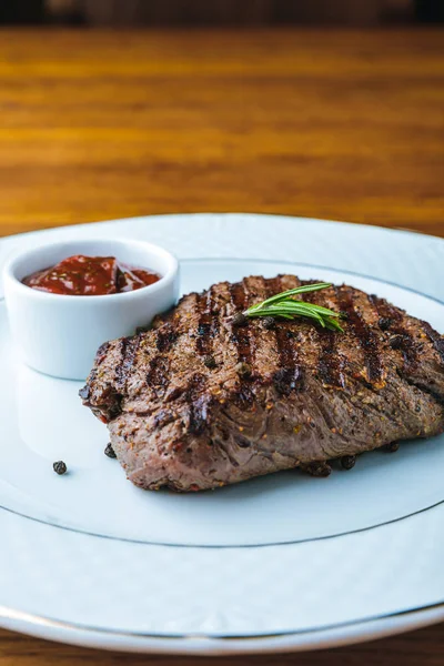 Delicioso bife grelhado com alecrim e molho de churrasco no prato — Fotografia de Stock