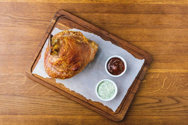 Vista dall'alto della nocca di maiale arrosto gourmet con salse su un tavolo di legno — Foto stock