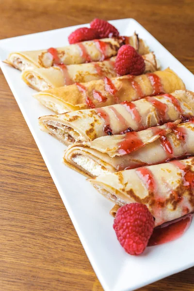 Close-up view of delicious sweet rolled pancakes with raspberries and jam — Stock Photo