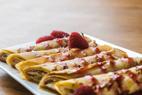 Close-up view of sweet rolled pancakes with raspberries — Stock Photo