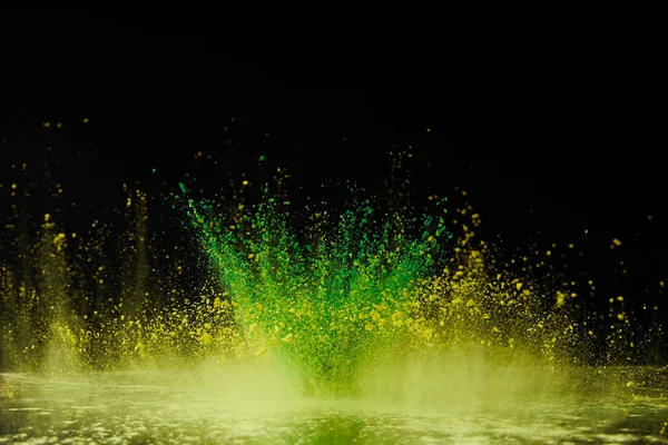 Yellow and green holi powder explosion on black, Hindu spring festival — Stock Photo