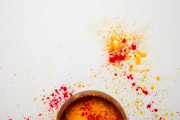 Vista dall'alto di vernice holi arancio e rosso in ciotola isolata su bianco — Foto stock