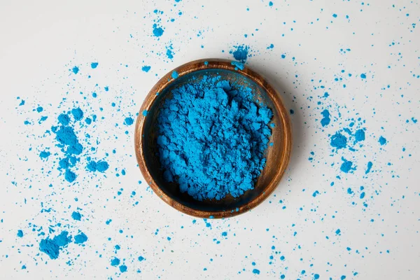 Vue du dessus de la peinture bleue holi dans un bol isolé sur blanc, fête du printemps hindou — Photo de stock