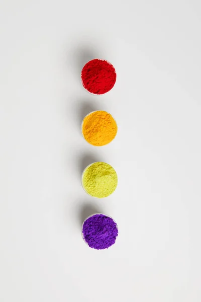 Top view of colorful holi paint in bowls in row, on white — Stock Photo