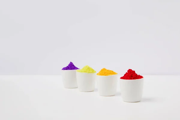 Row of colorful holi paint in bowls on white, Hindu spring festival — Stock Photo