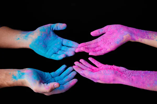 Vista recortada de pareja con pintura holi rosa y azul en las manos, aislado en negro - foto de stock