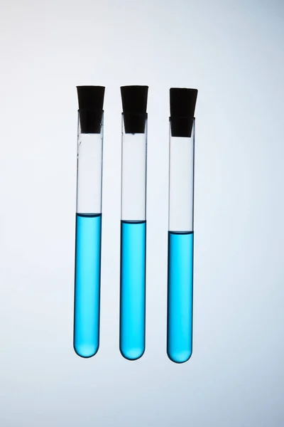Composition of test tubes filled with blue liquid floating in air on grey — Stock Photo