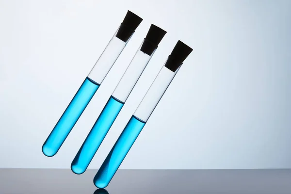 Row of test tubes filled with blue liquid on grey — Stock Photo