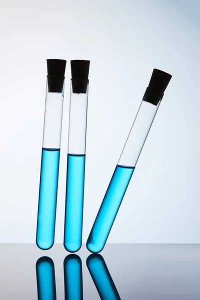 Tubos de química preenchidos com líquido azul sobre cinza — Fotografia de Stock