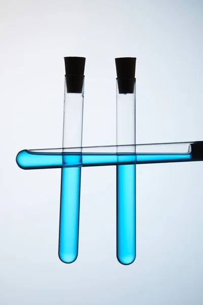 Test tubes filled with blue liquid on grey — Stock Photo