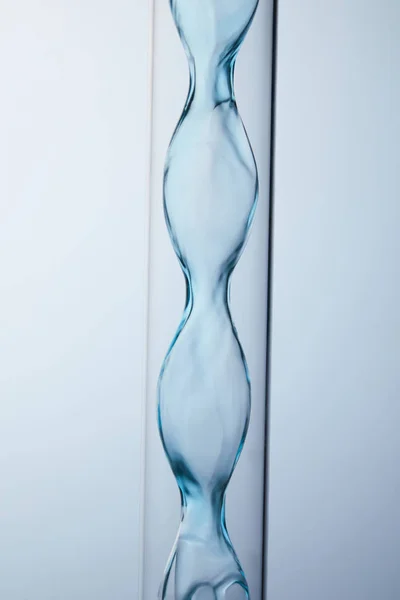 Close-up shot of chemistry glassware with floating blue liquid inside on grey — Stock Photo