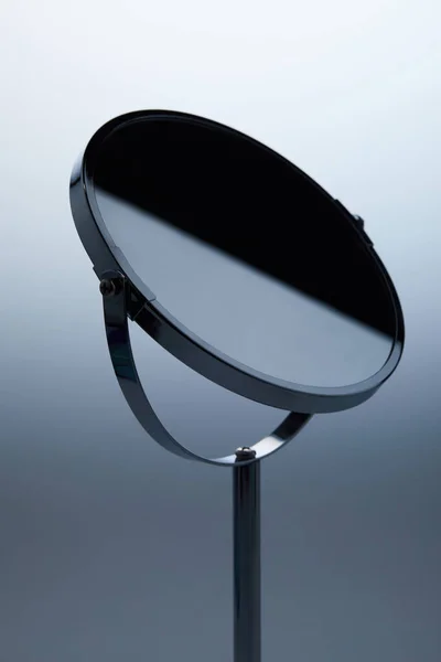 Close-up shot of cosmetic mirror with stand on grey — Stock Photo