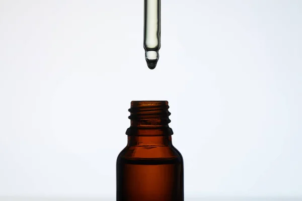 Close-up shot of bottle of aromatic oil with pipette on white — Stock Photo