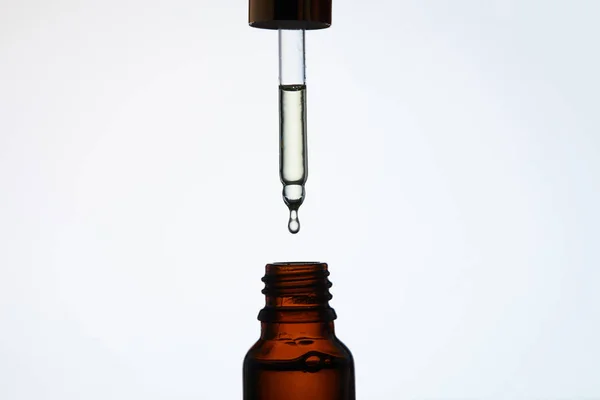 Primer plano de la botella de aceite aromático con pipeta por encima en blanco - foto de stock