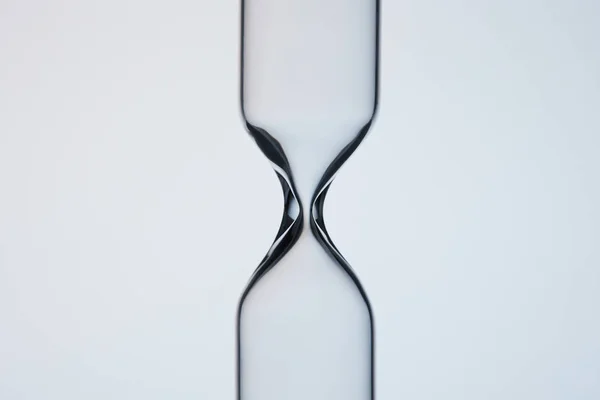 Close-up shot of empty glasware in shape of hourglass on grey — Stock Photo