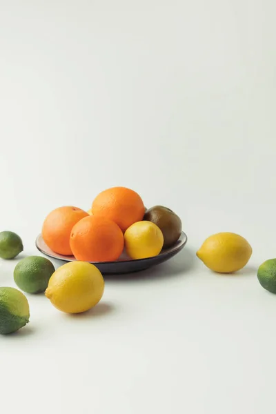 Cítricos en plato sobre fondo blanco - foto de stock