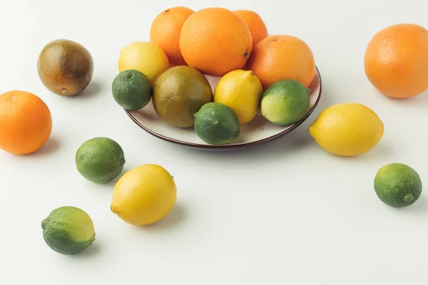 Raw citruses on plate on white background — Stock Photo