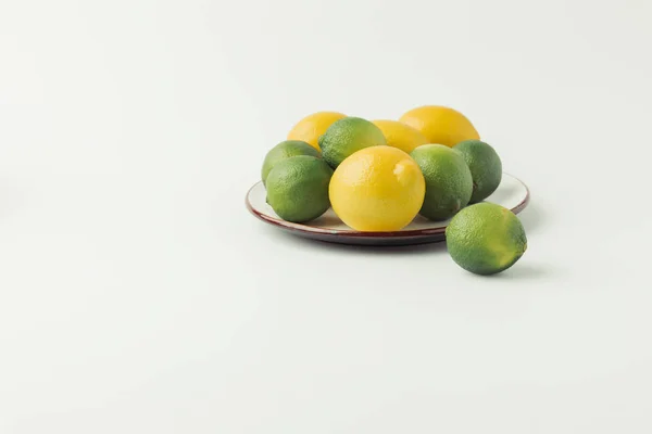 Citrus fruits on plate on white background — Stock Photo