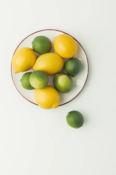 Top view of lemons and limes on plate isolated on white background — Stock Photo