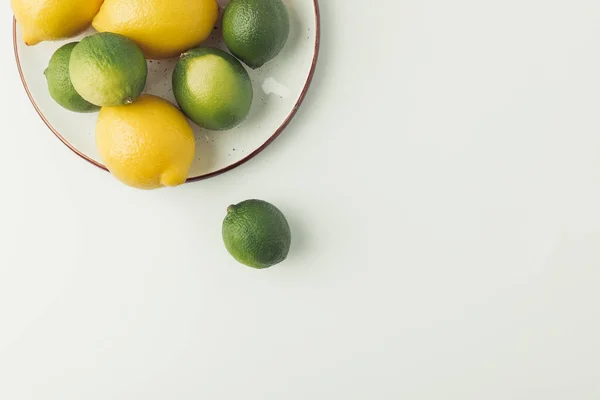 Цитрусовые фрукты на тарелке на белом фоне — стоковое фото