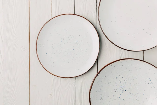 Ceramic glazed plates on white wooden background — Stock Photo