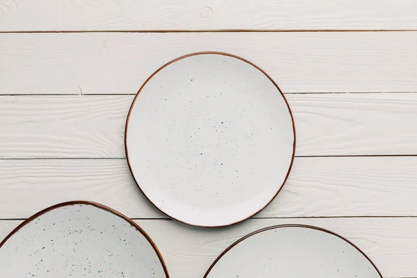 Empty ceramic plates on white wooden background — Stock Photo