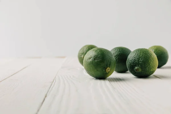 Ripe limes on white wooden background — Stock Photo