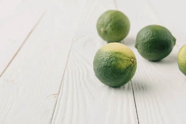 Limes verde grezzo su fondo di legno bianco — Foto stock
