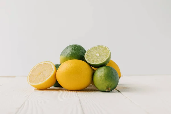 Limões e limas sobre fundo de madeira branca — Fotografia de Stock
