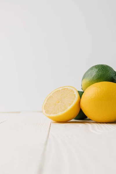 Green limes and lemons on white wooden background — Stock Photo