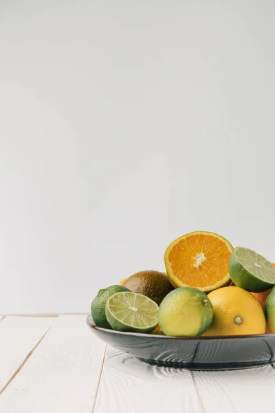 Teller mit Zitrusfrüchten auf weißem Holzhintergrund — Stockfoto