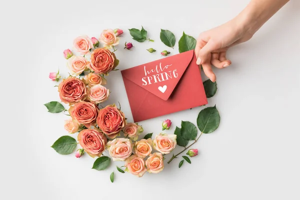 Конверт с надписью HELLO SPRING в окружении красивых розовых цветов, изолированных на белом — стоковое фото