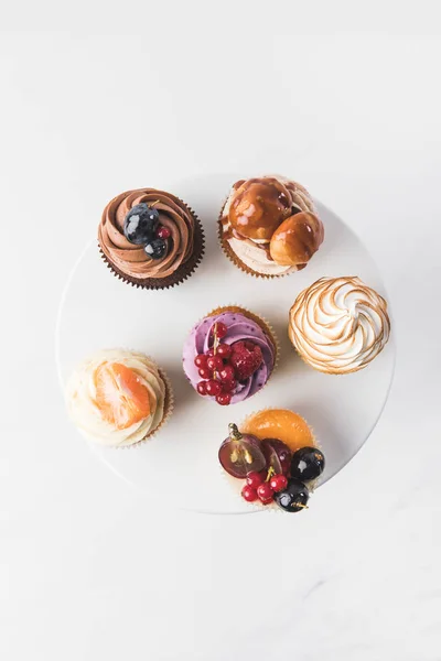 Top view of various sweet cupcakes on cake stand isolated on white — Stock Photo