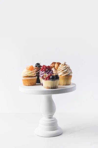 Vista de cerca de varios cupcakes dulces en pie de pastel aislado en blanco — Stock Photo