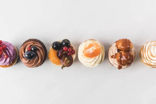 Vista superior de arranjo de cupcakes saborosos isolados em branco — Fotografia de Stock