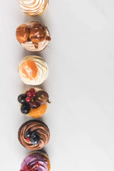 Vista dall'alto di disposizione di gustosi cupcake isolati su bianco — Foto stock