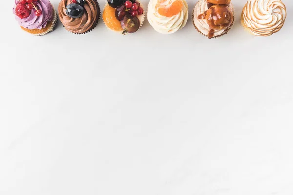 Ansicht von oben nach Anordnung von leckeren Cupcakes isoliert auf weiß — Stockfoto