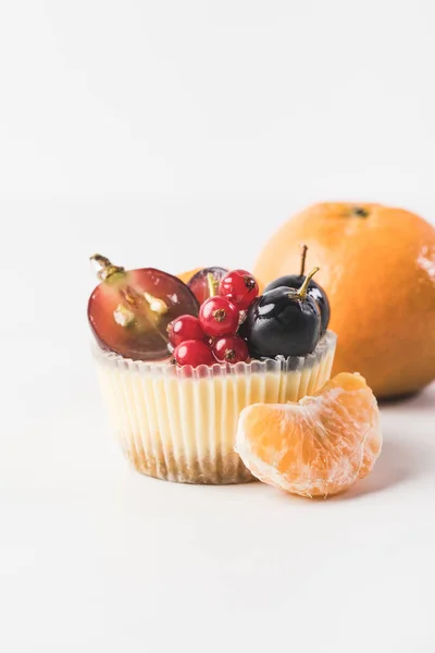 Primer plano vista de cupcake dulce con bayas, frutas y mandarina cerca por aislado en blanco - foto de stock
