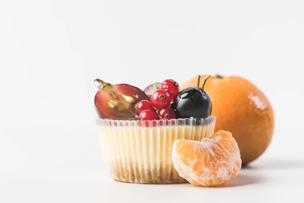 Primer plano vista de cupcake dulce con bayas, frutas y mandarina cerca por aislado en blanco - foto de stock