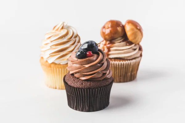 Vista de cerca de varios cupcakes dulces aislados en blanco - foto de stock