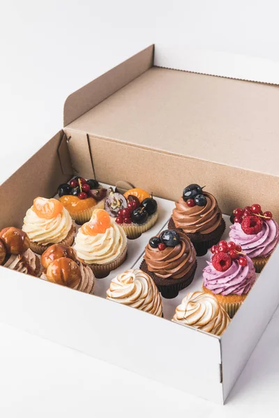 Close up view of various types of cupcakes in cardboard box isolated on white — Stock Photo