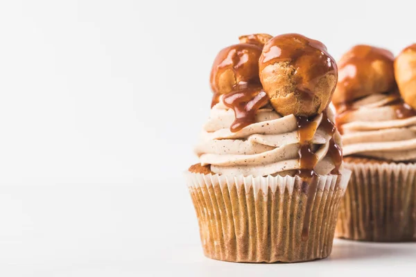 Vista de perto de cupcakes com creme, profiteroles e caramelo isolado em branco — Fotografia de Stock