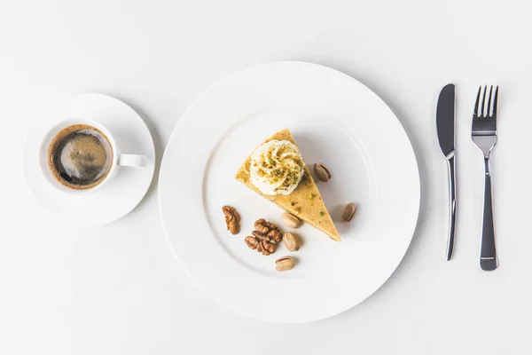 Draufsicht auf das Stück Kuchen mit Nüssen und Tasse Kaffee isoliert auf weißer Oberfläche — Stockfoto