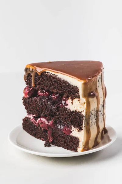 Vista de cerca de pastel de cereza y chocolate dulce con caramelo en el plato aislado en blanco - foto de stock