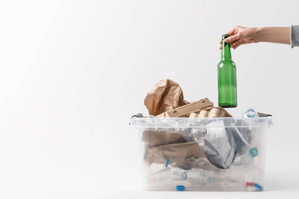 Tiro recortado de la mujer poniendo botella de vidrio en el recipiente con botellas de plástico, concepto de reciclaje - foto de stock