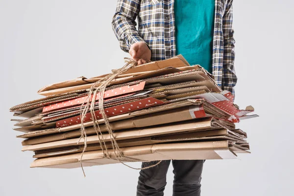 Cropped shot of man holding pile of folded cardboard boxes isolated on grey, recycling concept — Stock Photo