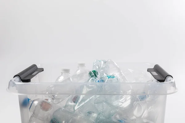 Vista ravvicinata del contenitore con bottiglie di plastica isolate su grigio, concetto di riciclaggio — Foto stock