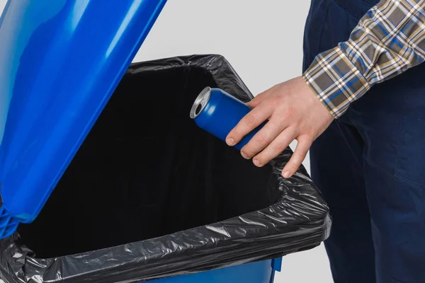 Partial view of cleaner putting can into trash bin isolated on grey — Stock Photo