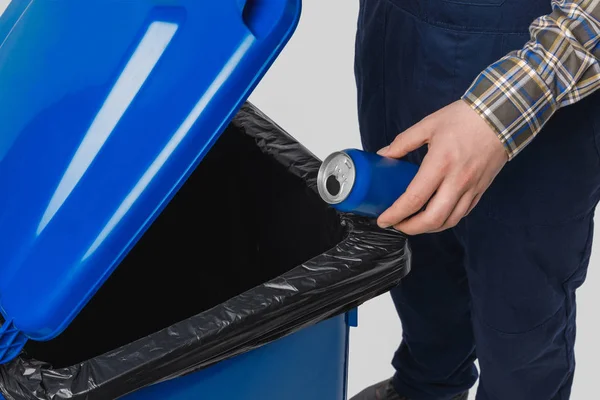 Partial view of cleaner putting can into trash bin isolated on grey — Stock Photo